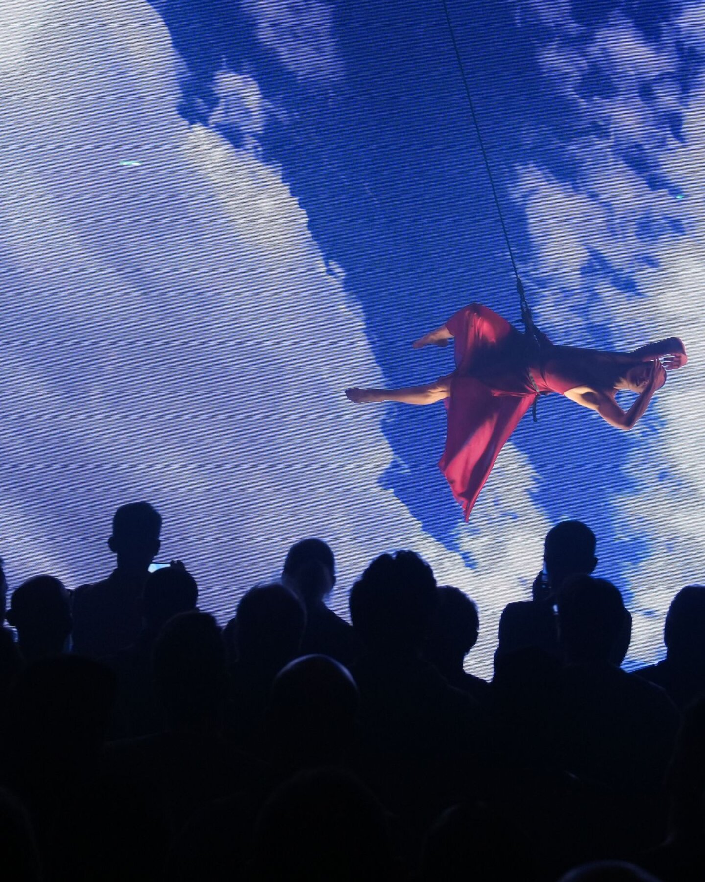Performance aerea su sfondo digitale immersivo durante evento a MIR, pubblico in osservazione Performance aerea su sfondo digitale immersivo durante evento a MIR, pubblico in osservazione