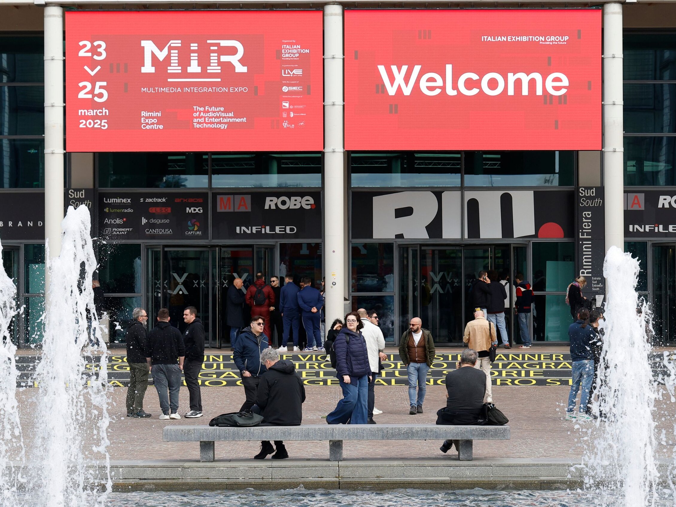 Visitatori all’ingresso del MIR 2025 alla Fiera di Rimini sotto l’insegna di benvenuto