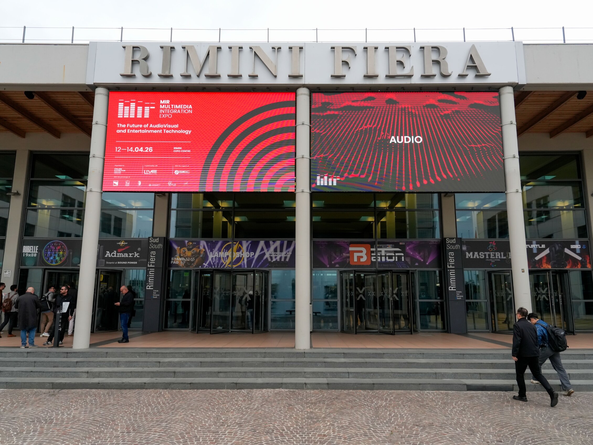 Ingresso di MIR in fiera a Rimini con maxi schermi dedicati alle tecnologie audio e visitatori all’entrata
