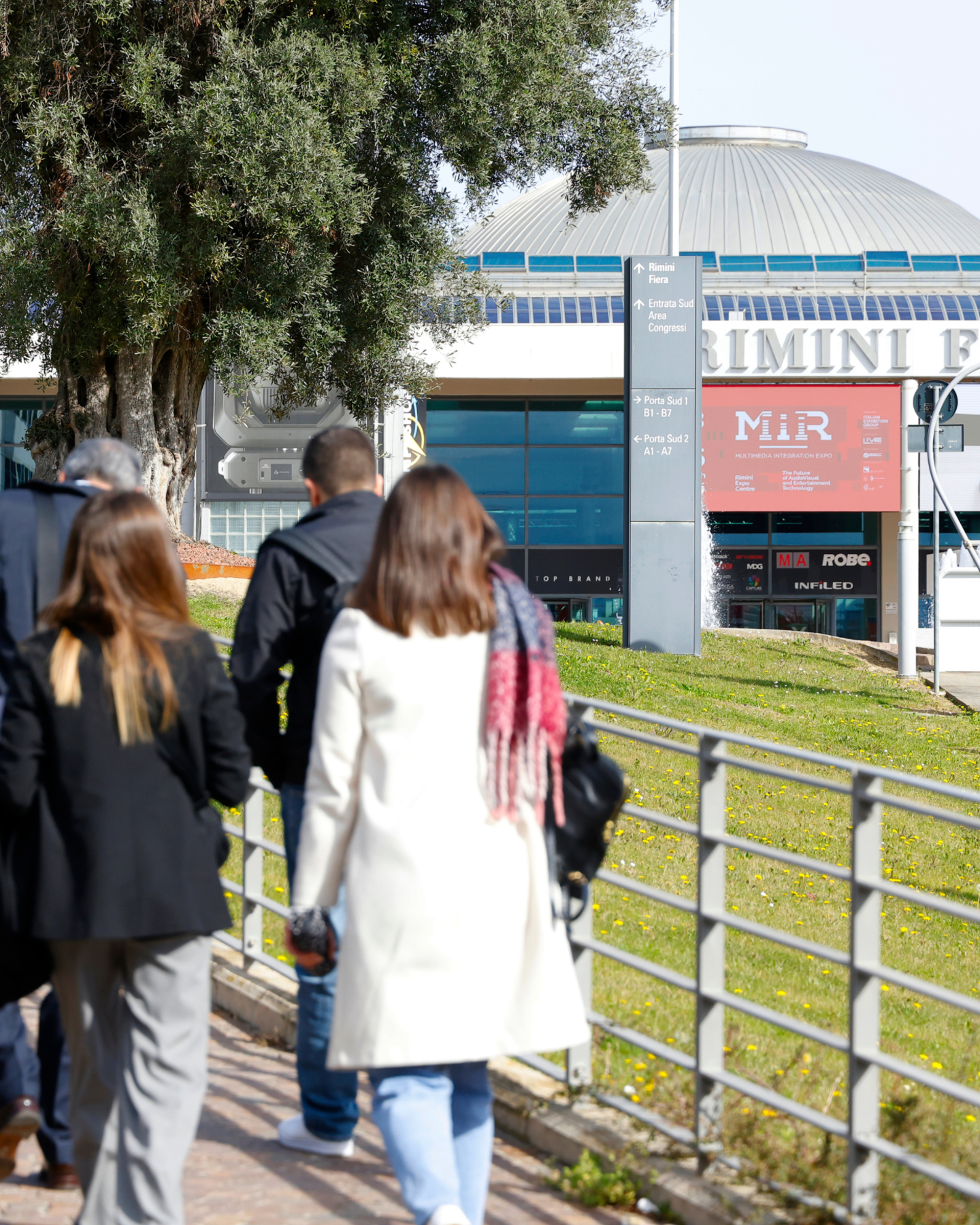 Visitatori in ingresso a piedi a MIR presso la fiera di Rimini, segnaletica e padiglione visibili